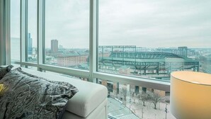 A hotel room with a large window offering a view of a stadium and cityscape.