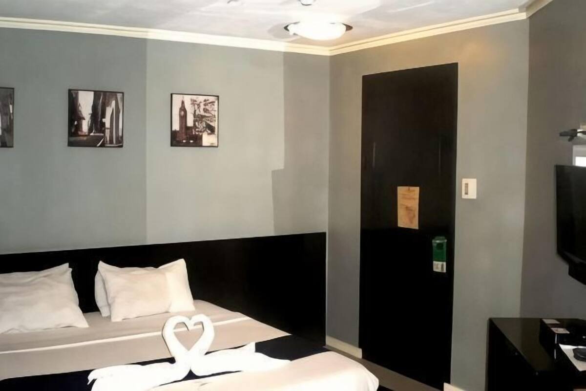 Quarto de hotel com cama, televisão de tela plana e obras de arte nas paredes.