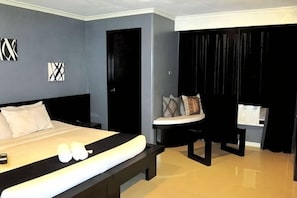 A bedroom with a bed, bedside table, and a chair. - Richmond Plaza Hotel (Cebu City)
