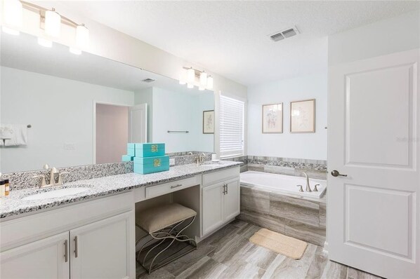 A modern bathroom with a large mirror, a bathtub, and a vanity with a countertop. - 1577SW: Amazing 5bd/5bath home! Sleeps 13 w/ pool and jacuzzi! (Davenport)