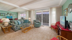 Una sala de estar con sofá, sillones, una mesa de centro y televisor.