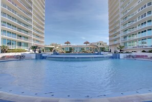 Une vaste piscine intérieure dotée d’un élément décoratif central, entourée de plusieurs étages d’hôtels avec des balcons.