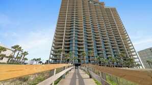 A tall hotel with multiple balconies and a central walkway leading to the entrance. - Phoenix West 1108 by Liquid Life (Orange Beach)