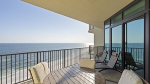 A balcony with a wooden table and chairs, overlooking the ocean. - Phoenix West 1108 by Liquid Life (Orange Beach)