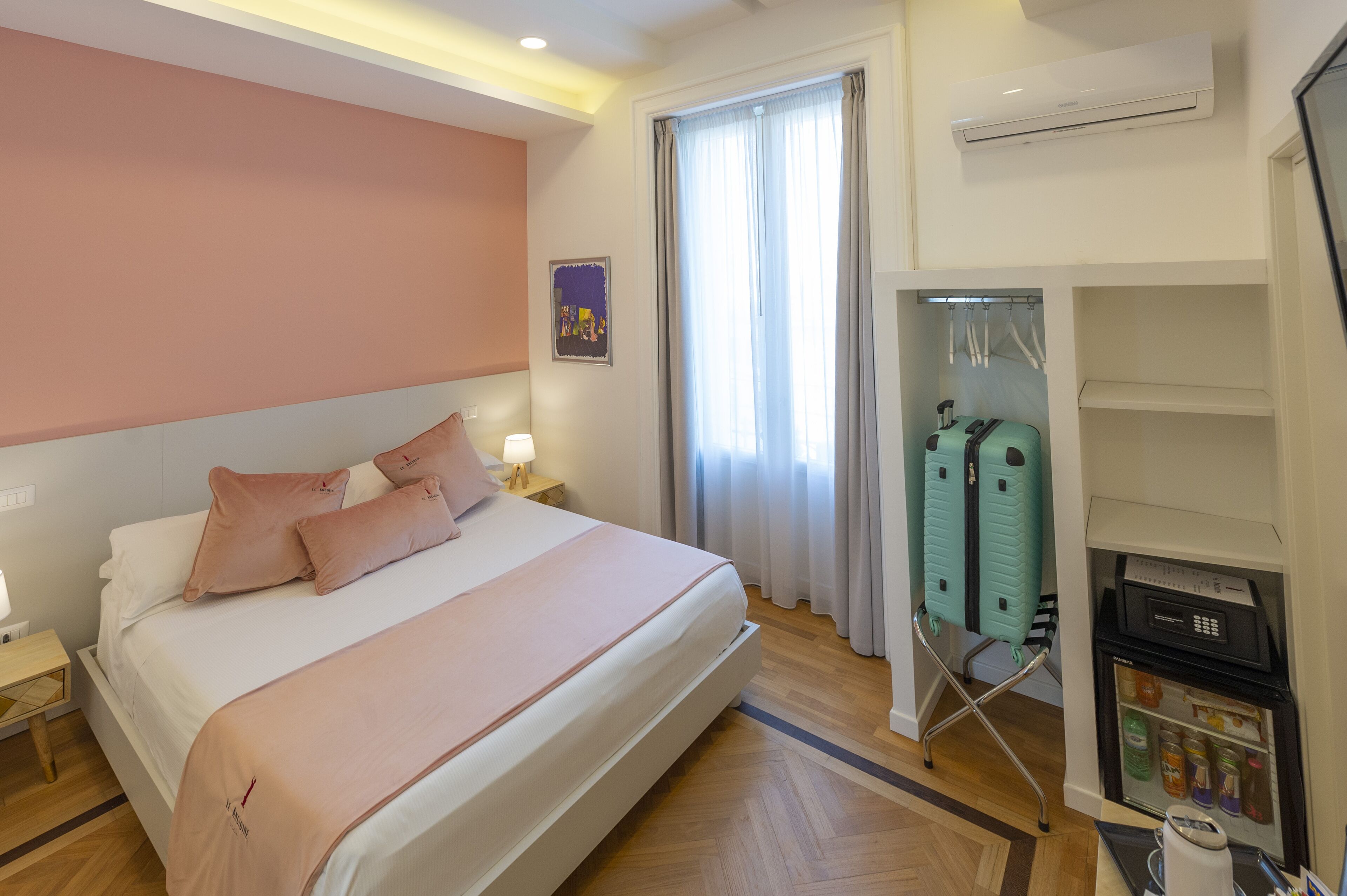 A hotel room with a bed, a wardrobe, a mini-fridge, and a window with curtains.