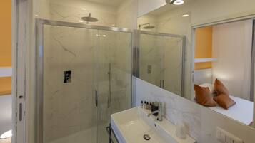 Ein modernes Badezimmer mit einer begehbaren Glasdusche, einem weißen Waschbecken und einem großen Spiegel.