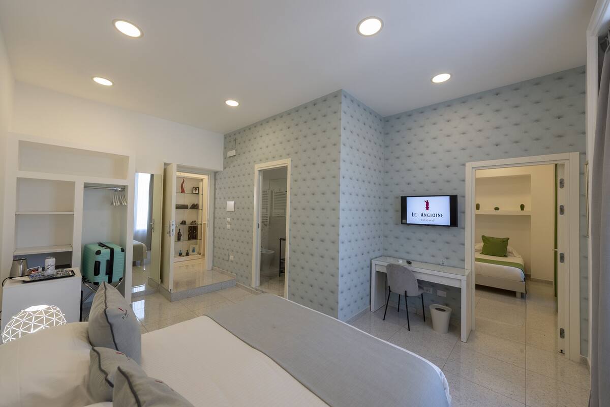A hotel room with a bed, desk, chair, TV, and wardrobe.