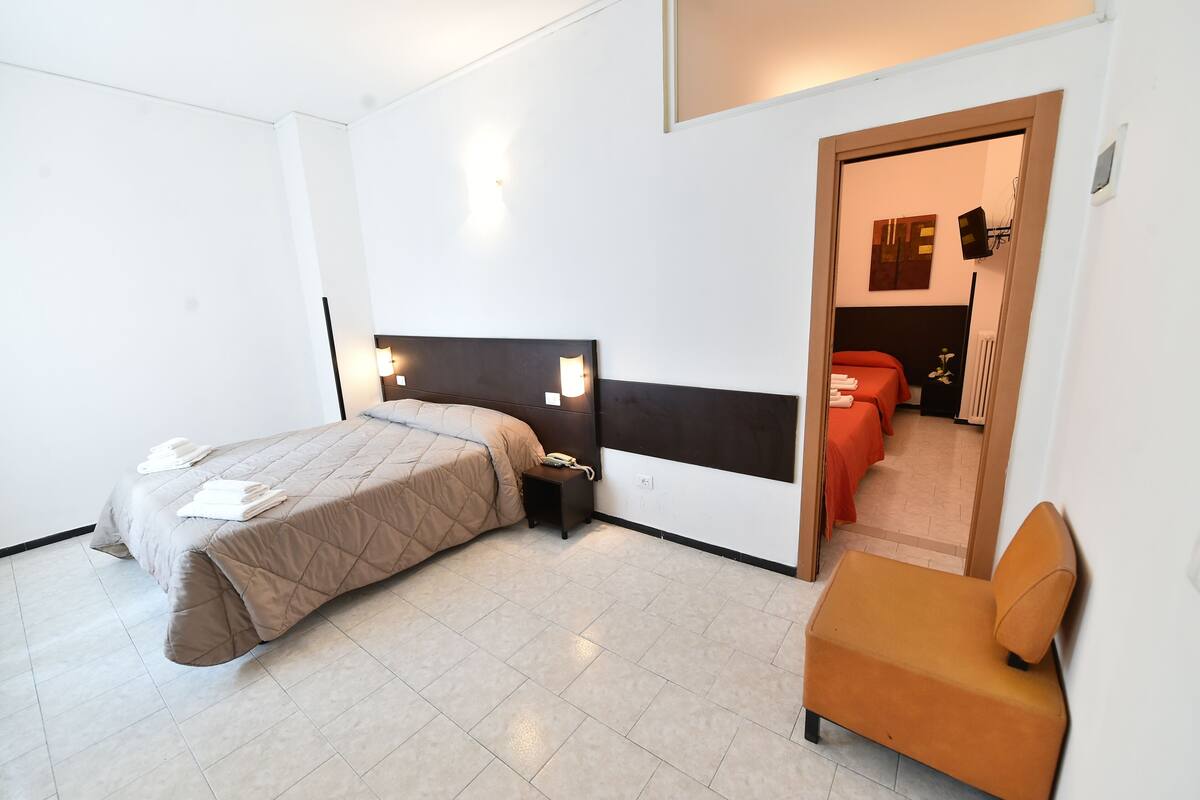 Una habitación de hotel con cama, mesita de noche y una silla.