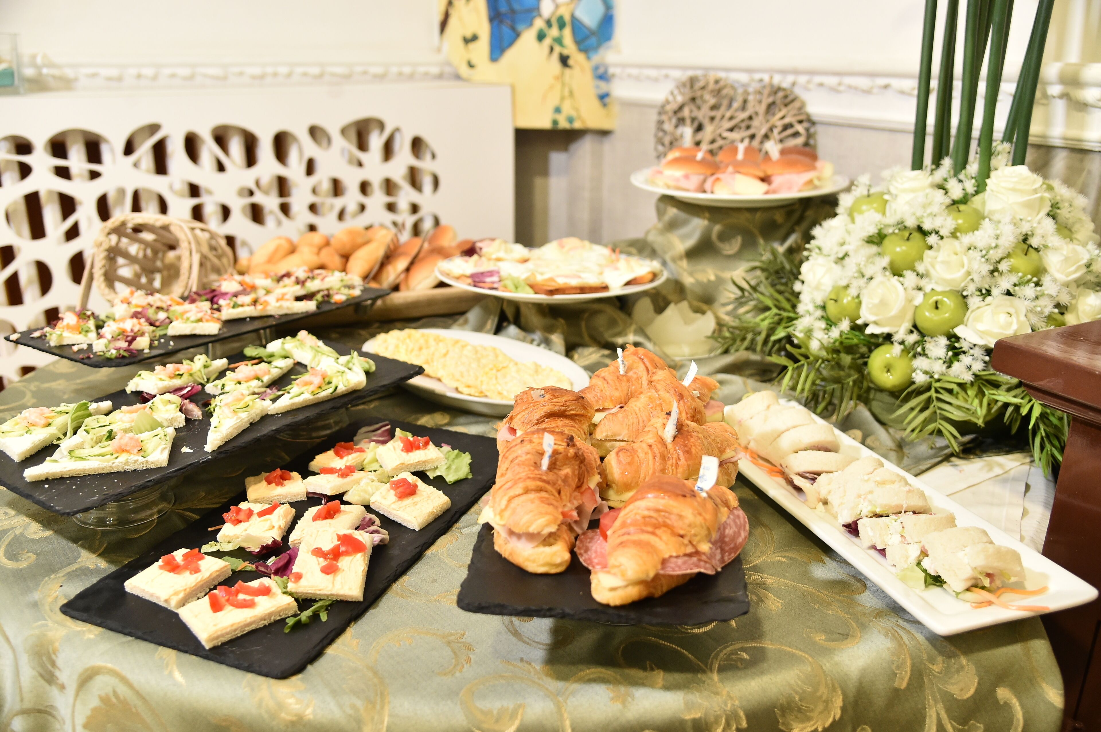 Een buffet met diverse gerechten, waaronder belegde broodjes, croissants en salades.