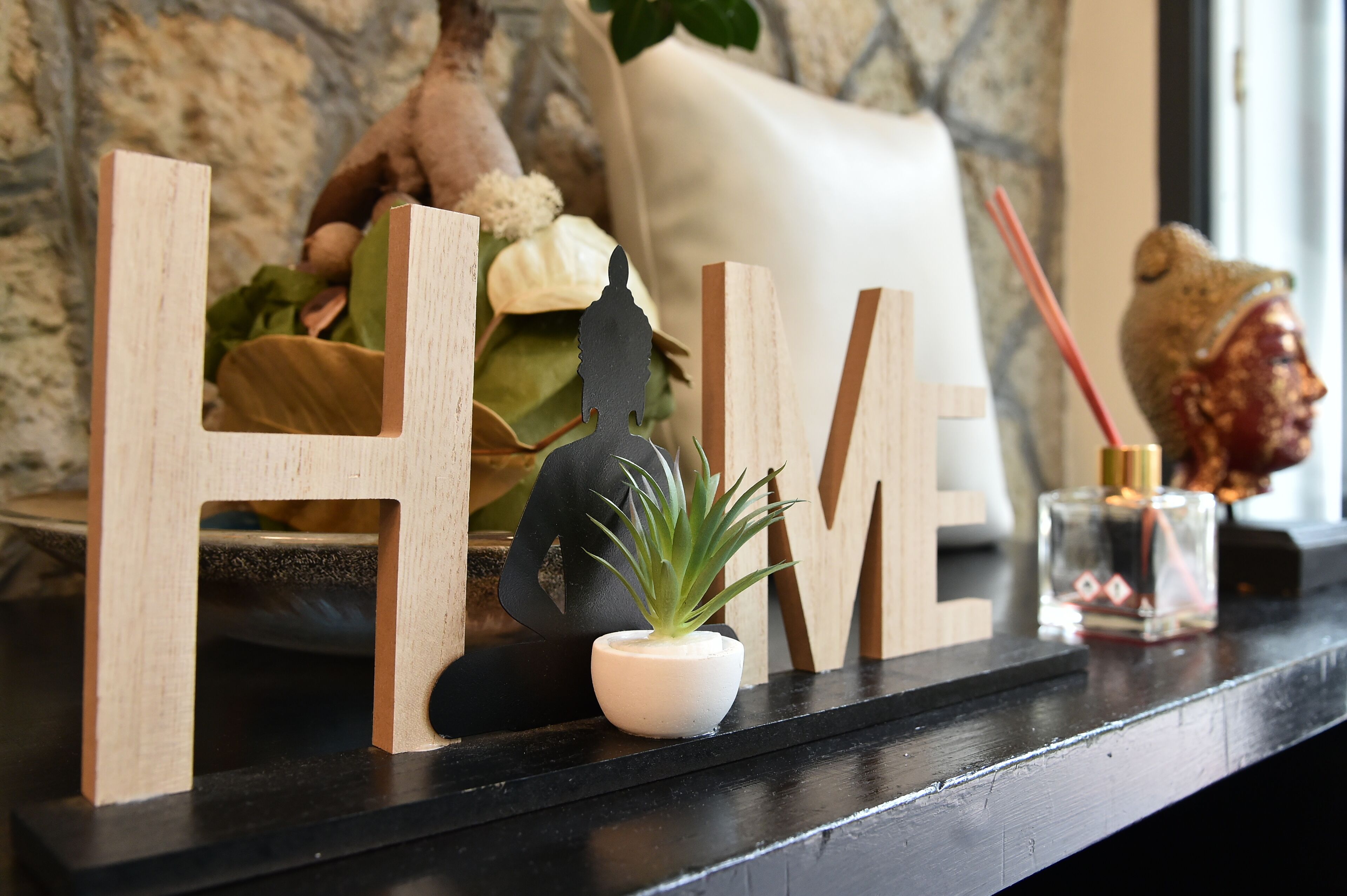 Wooden letters spelling "HIVE" on a black shelf, a small potted plant, and a decorative item.