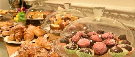 A buffet with various pastries and desserts, including croissants and covered sweets.