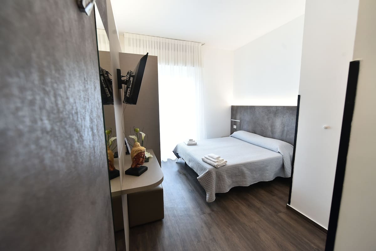 Una habitación de hotel moderna con una cama, un escritorio y un espejo.