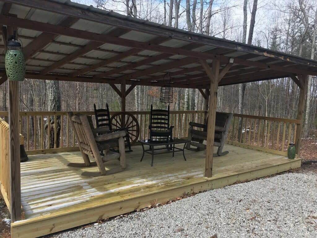 A wooden deck with a covered seating area, including two chairs and a table.