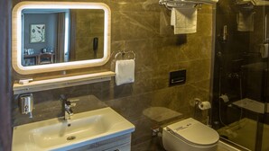 Un baño moderno con tocador, lavamanos, espejo, inodoro y cabina de ducha de vidrio.