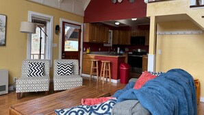 A living room with a sofa, ottoman, and a dining table.