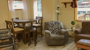 Una sala de estar con una mesa de comedor, sillas, un sillón estampado con motivos de cebra, un sofá, una lámpara y una pequeña planta en maceta.