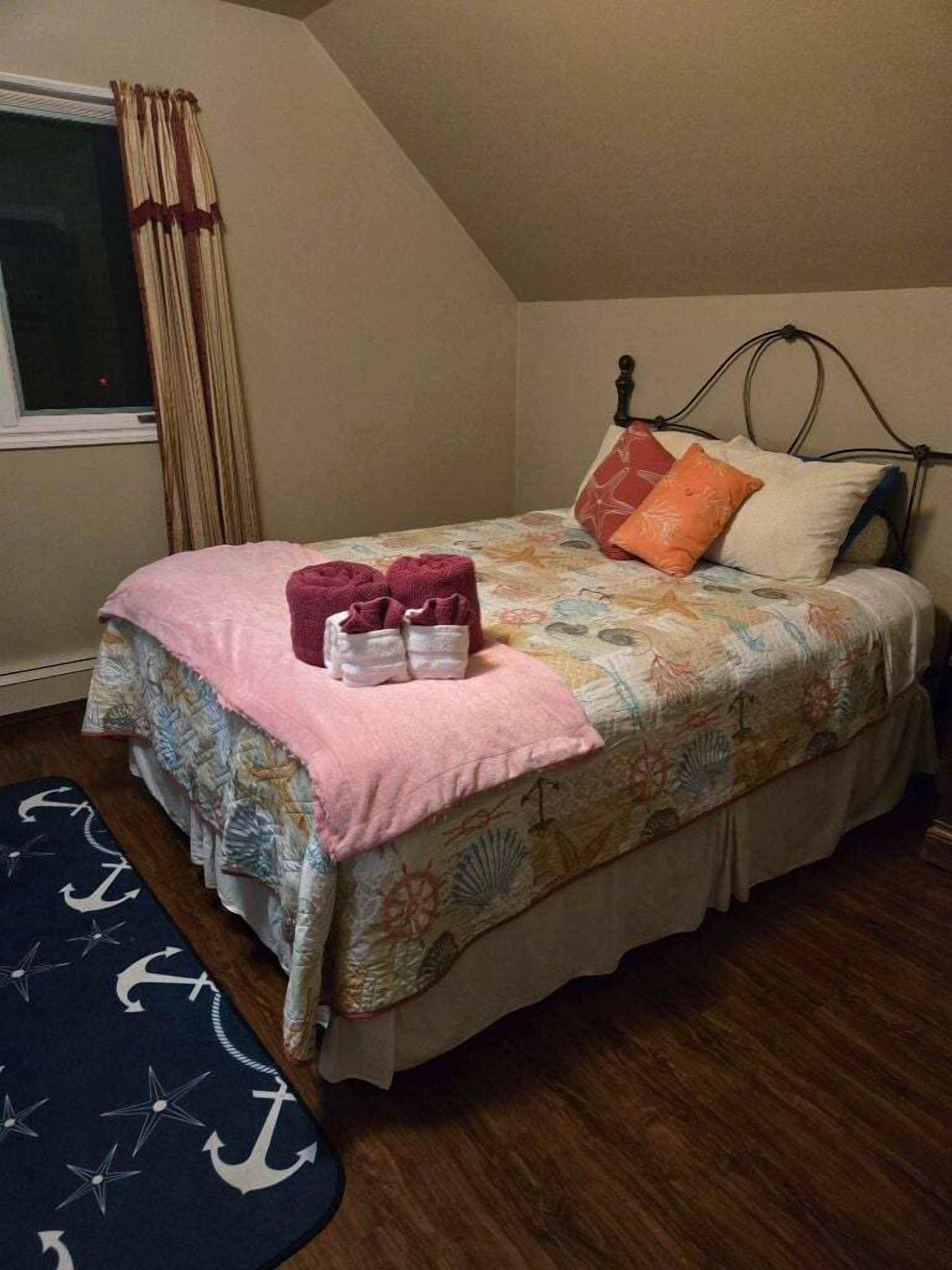 A bedroom with a bed, pillows, a blanket, and a rug.