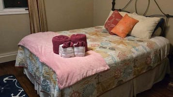 A bedroom with a bed, pillows, a blanket, and a rug.
