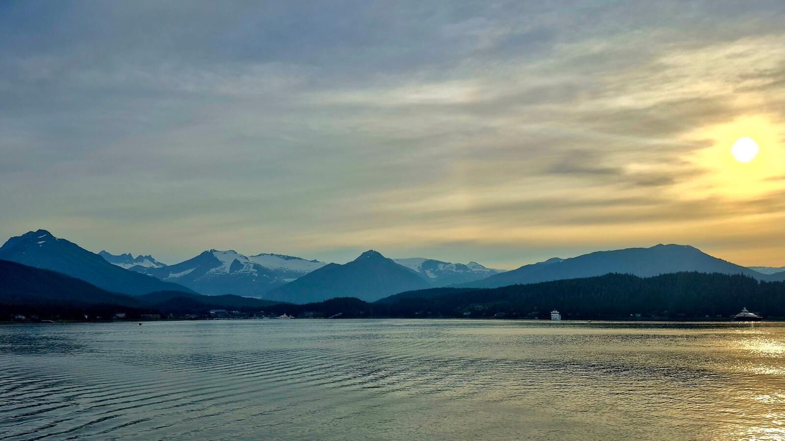 Un lac paisible, avec des montagnes en arrière-plan et un bateau sur l’eau.