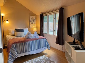 Ein Hotelzimmer mit Bett, Fernseher, Schreibtisch und einem Vorhangfenster.