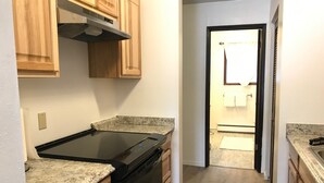 A kitchen with granite countertops, wooden cabinets, and a black dishwasher. - Kelli's Harbor Suites - In Auke Bay Walking Community - DISCOUNT ON TOURS (Juneau)