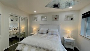 A bedroom with a large bed, two bedside tables with lamps, a ceiling light, and a window.