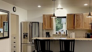 A modern kitchen with wooden cabinets, stainless steel appliances, and a central island with bar stools.
