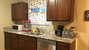 A kitchen with wooden cabinets, a microwave, a coffee maker, a toaster, and a dishwasher. - Rainbow Row - Three Private Units in Complex, near Mendenhall Glacier, Trails, and Conveniences! (Juneau)