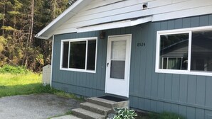 A single-story house with a front door, two windows, and a small porch. - Rainbow Row - Three Private Units in Complex, near Mendenhall Glacier, Trails, and Conveniences! (Juneau)