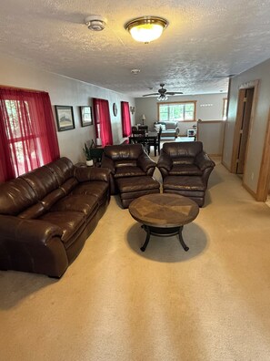 A living room with a brown leather sofa, two armchairs, and a coffee table.