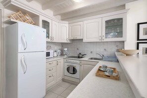 Una cocina con armarios blancos, un refrigerador, un microondas, una estufa y un lavaplatos.