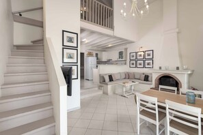 A spacious living area with a staircase, a kitchen, a dining area, and a fireplace. - Ammos Beach House - Four Bedroom Villa, Sleeps 8 (Rhodes)