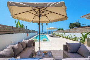 A poolside area with lounge chairs, a table with drinks, and umbrellas.