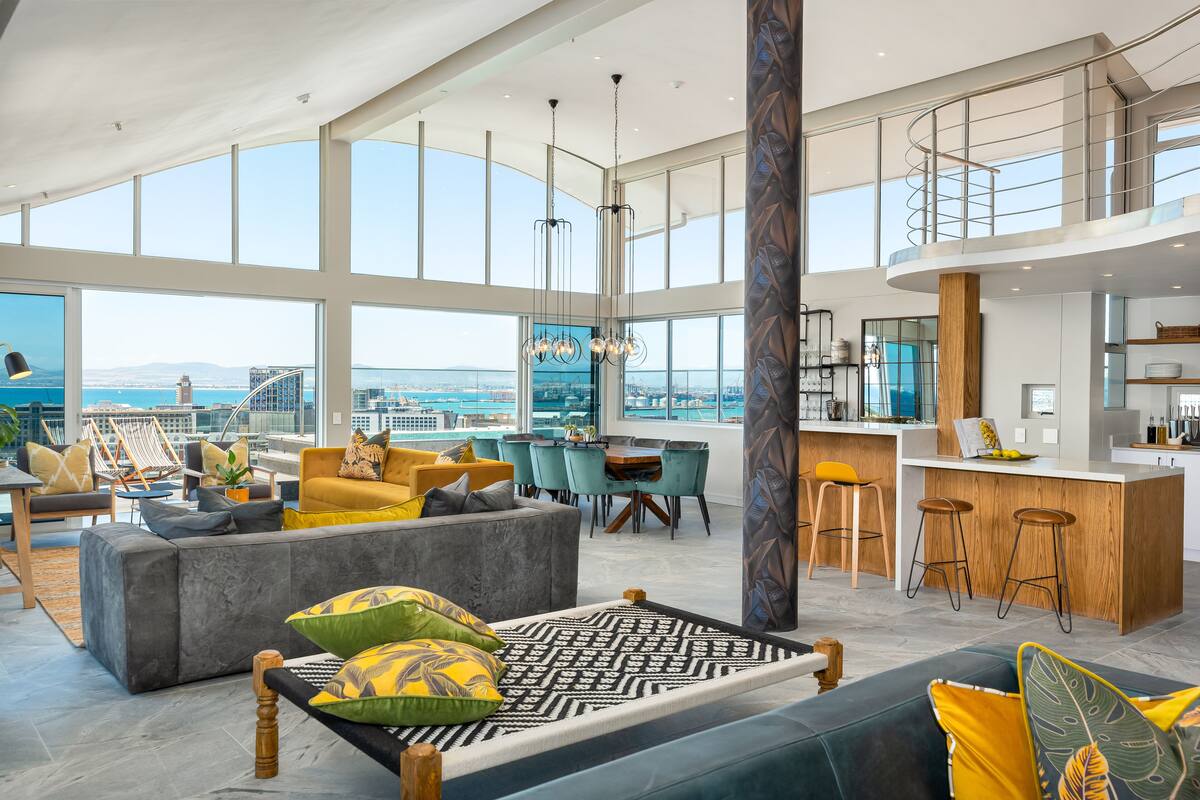 A spacious living area with a high ceiling, large windows, and a view of the city.