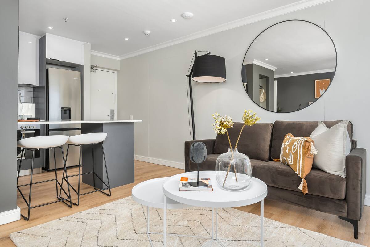 A modern living area with a sofa, coffee table, and bar stools.