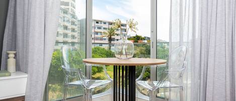 A modern room with a round table, two clear chairs, and a vase with flowers.