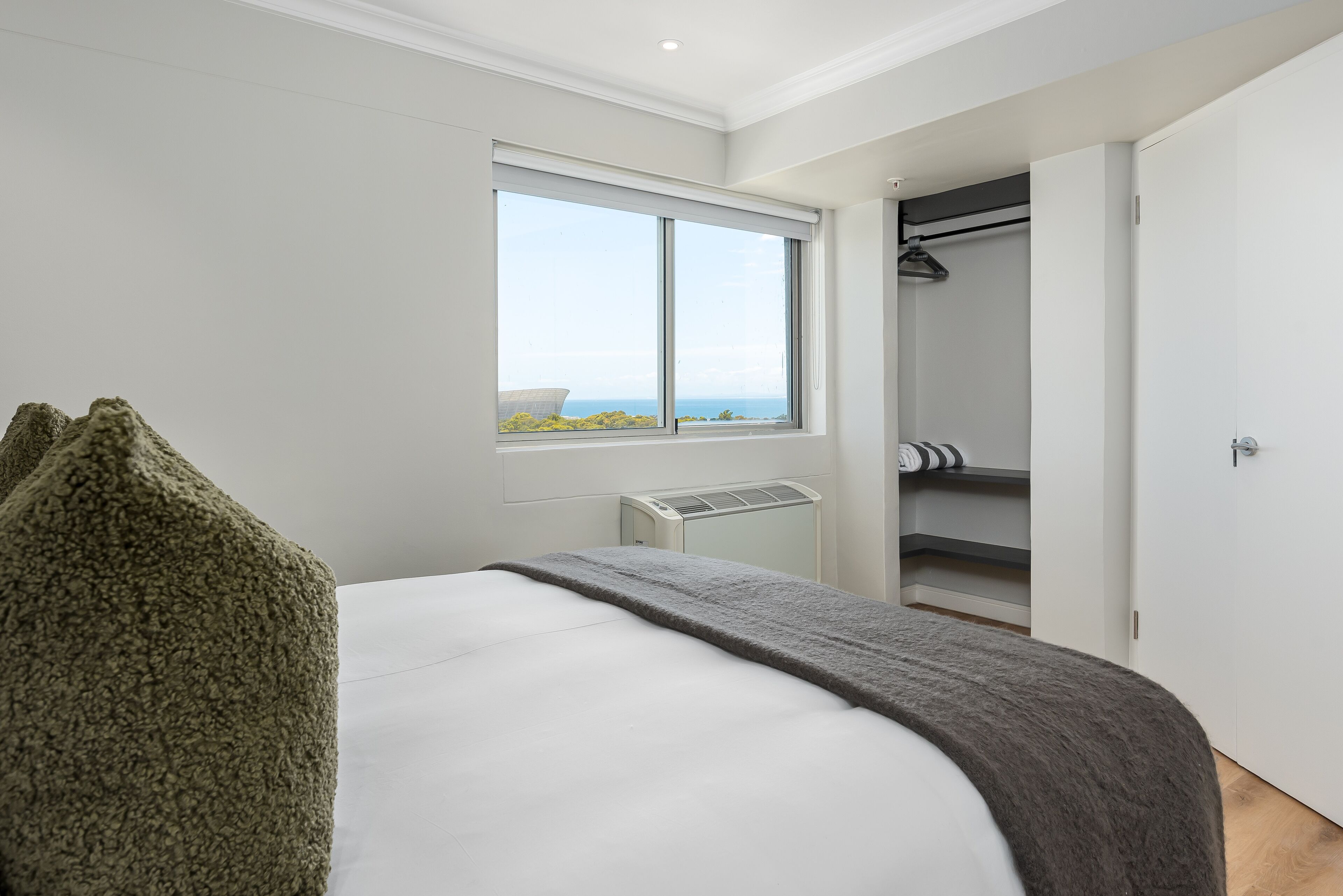 A bedroom with a large bed, a window with a view, a walk-in closet, and a radiator.
