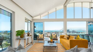A spacious living area with large windows, a yellow sofa, a coffee table, and a view of the cityscape.