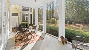 A covered patio with a ceiling fan, a dining table with chairs, and a view of a forested area. - Golfer's Getaway Condo- Players Village TPC (Murrells Inlet)