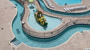 A pool area with multiple water slides, including a large circular slide, and sun loungers around the perimeter. - Beach Vibes 1BR Condo in Litchfield (Pawleys Island)