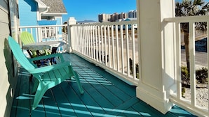 Une véranda avec une table et des chaises, une balustrade et une vue sur les bâtiments environnants.