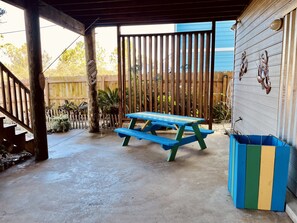 Enjoy al fresco dining on the patio, surrounded by lush greenery and a wooden fence.