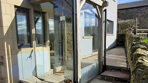 A modern building with a glass entrance, stone steps, and a stone wall. - Lane End Cottage Holmfirth - Panoramic Views, Modernised with offroad parking  (Snowgate Head)