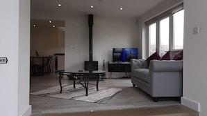 A modern living room with a fireplace, a sofa, and a television. - Lane End Cottage Holmfirth - Panoramic Views, Modernised with offroad parking  (Snowgate Head)