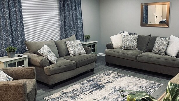 Ein modernes Wohnzimmer mit zwei Sofas, einem Couchtisch und einem gemusterten Teppich.