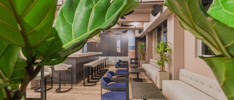 A modern interior with a bar area, seating, and potted plants.
