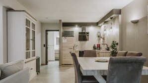 Una cocina moderna con comedor, que presenta una mesa de madera y sillas tapizadas en gris.