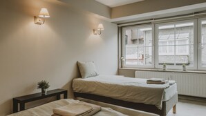 Un dormitorio con dos camas, una ventana con vistas y lámparas fijadas a la pared.