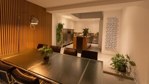 Et moderne spiseområde med et langt bord, stole og en potteplante.