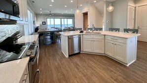 A modern kitchen with a central island, stainless steel appliances, and pendant lighting.